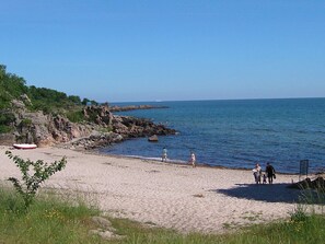 A beach with rocky cliffs, a sandy shore, and a calm sea. - 4 Person Holiday Home in Allinge (Allinge)