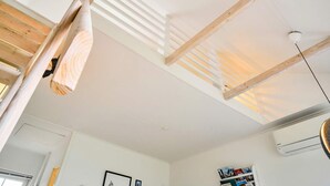 Une pièce avec un plafond en pente, des poutres en bois et un appareil de climatisation.