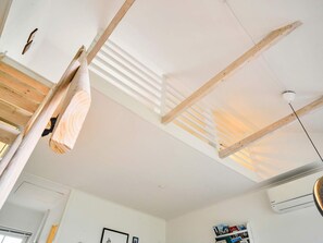 A room with a sloped ceiling, wooden beams, and an air conditioning unit. - 4 Person Holiday Home in Allinge (Allinge)