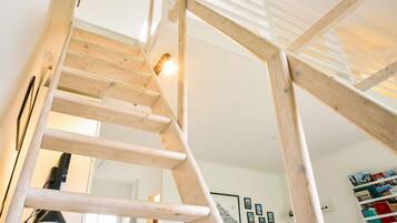 A wooden staircase with a white interior, a wall-mounted bookcase, and framed pictures.