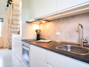 A modern kitchen with white cabinets, a stainless steel sink, and a built-in oven. - 4 Person Holiday Home in Allinge (Allinge)