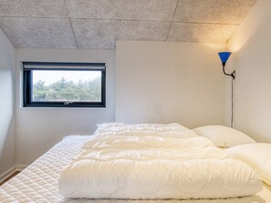 A bedroom with a bed, a window, and a wall-mounted lamp. - 5 Star Holiday Home in Lokken (Lokken)