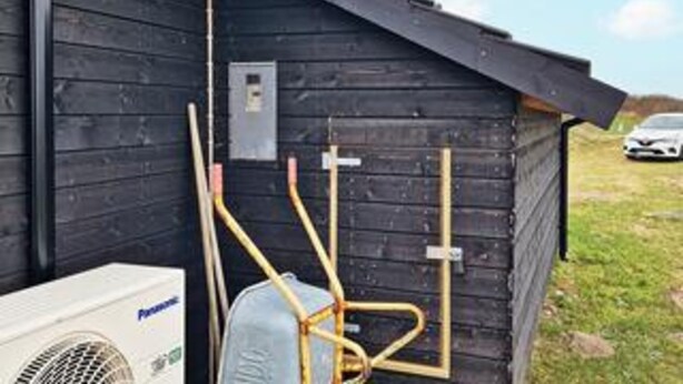 A small wooden structure with a slanted roof, a utility box, and a white air conditioning unit. - 5 Star Holiday Home in Lokken (Lokken)