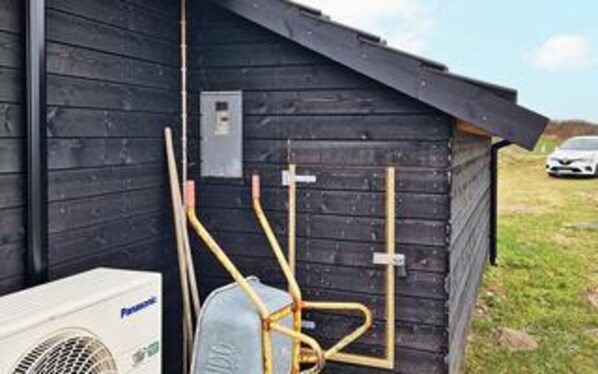 A small wooden structure with a slanted roof, a utility box, and a white air conditioning unit. - 5 Star Holiday Home in Lokken (Lokken)