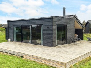 Une maison moderne dotée d’une terrasse, de grandes portes-fenêtres coulissantes et d’une cheminée.
