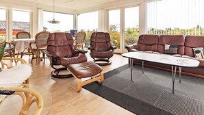 Una habitación amplia con un gran ventanal, sillones de cuero, un sofá y una zona de comedor.
