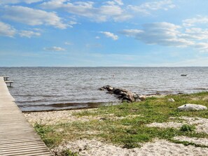 A wooden pier extending into calm waters with a clear sky.