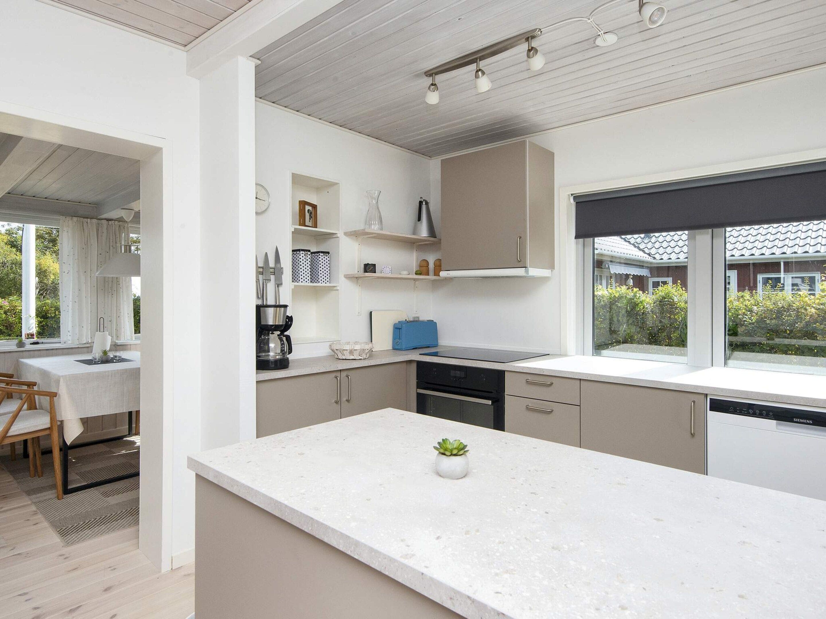 A modern kitchen with a large island, built-in appliances, and a view of the outdoors.