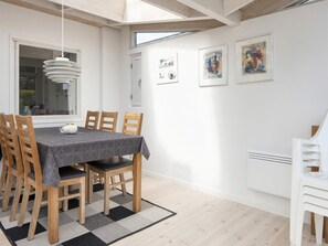 A dining area with a table set for six, wooden chairs, a patterned tablecloth, and a hanging light fixture. - 6 Person Holiday Home in Sjolund (Sjølund)