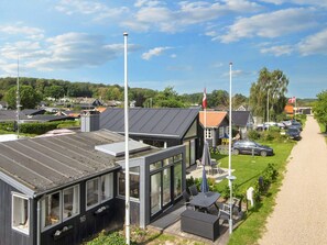 A modern building with large windows and a flat roof, surrounded by a gravel path and greenery. - 6 Person Holiday Home in Sjolund (Sjølund)