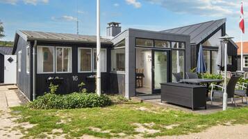 A modern building with a flat roof, large windows, and a patio area with outdoor furniture.