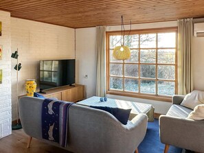 A cozy living room with a television, a sofa, a small table, and a window with curtains. - 4 Person Holiday Home in Aars (Aars)