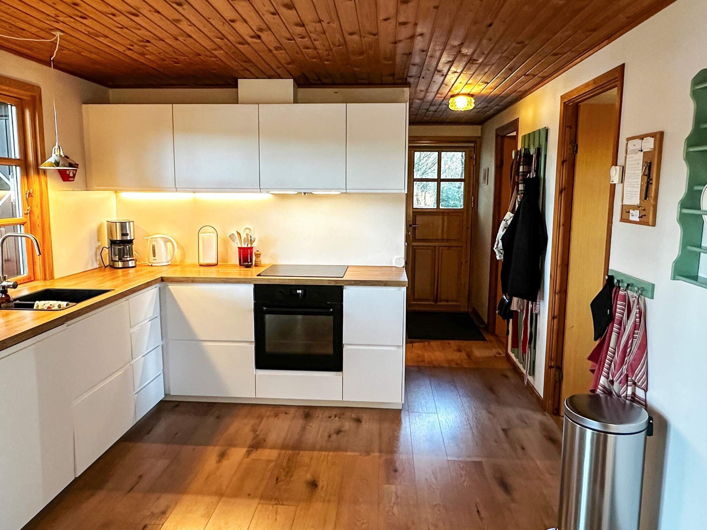 Uma cozinha compacta com armários brancos, lava-louças e cafeteira.