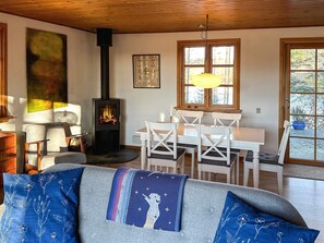 A cozy living room with a fireplace, a dining area, and a large window.