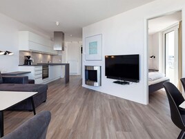 Una habitación de hotel moderna con kitchenette, televisión de pantalla plana, sofá y cama.