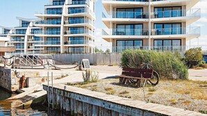 A modern multi-story building with balconies and large windows, located near a dock with a wooden walkway. - 5 Star Holiday Home in Wendtorf (Wendtorf)