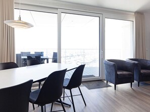 A modern living room with a dining area, large sliding glass doors, and a view of the cityscape. - 5 Star Holiday Home in Wendtorf (Wendtorf)