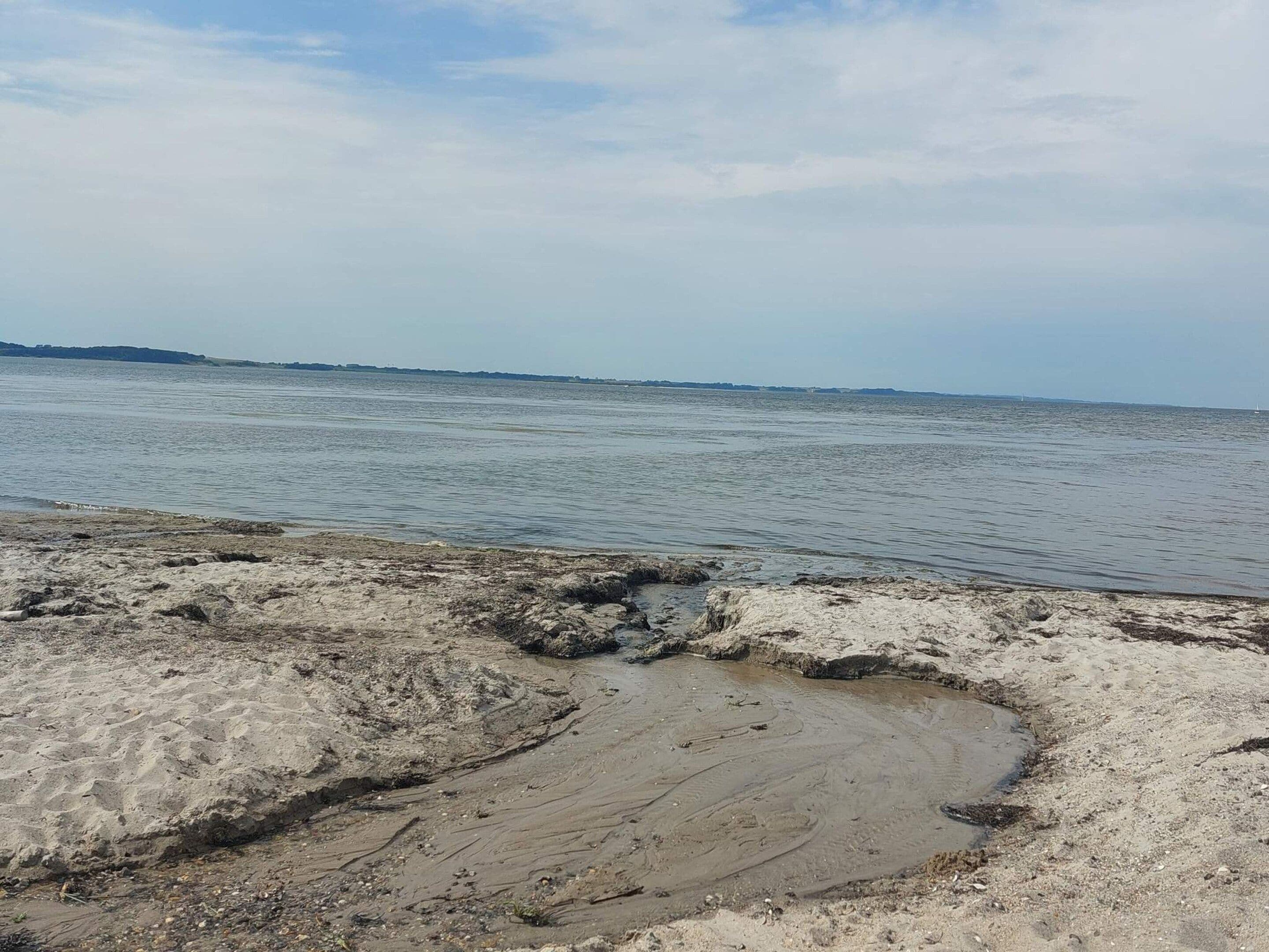 Una playa con costa rocosa y agua tranquila.