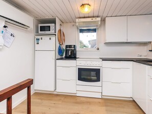 A compact kitchen with white cabinets, a microwave, a coffee maker, and an oven. - 4 Person Holiday Home in Farso (Farso)