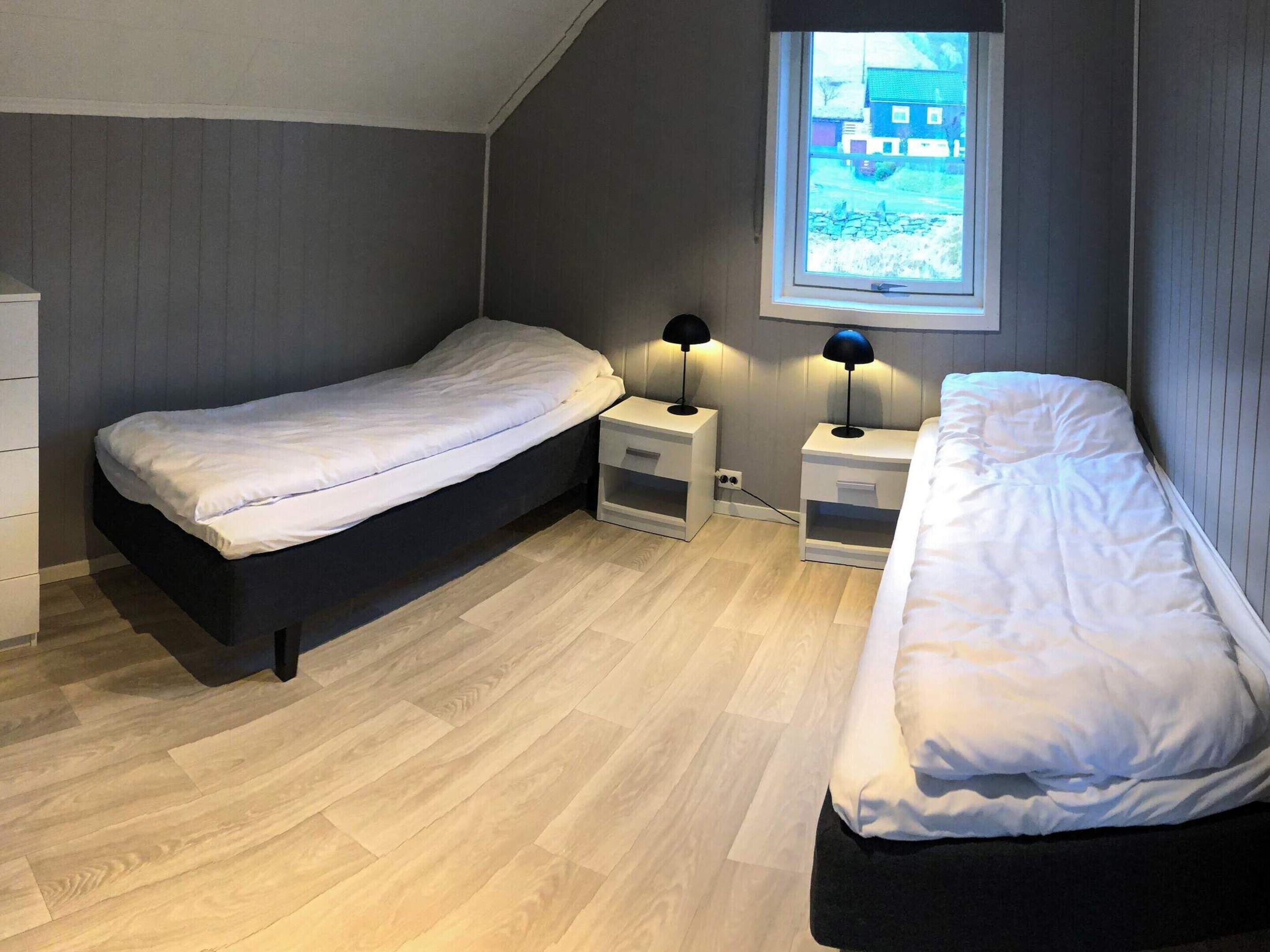 Un dormitorio con dos camas individuales, una ventana con vistas y mesitas de noche con lámparas.