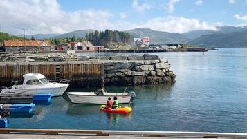 Un port où sont amarrés des bateaux, un phare et une côte rocheuse.