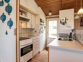 Una cocina con techo de madera, horno empotrado, un lavabo y una ventana.