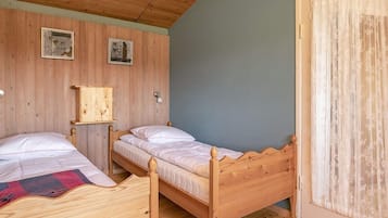 Ein Zimmer mit zwei Holzbett, einer Holzbalkendecke und einer Wand mit zwei gerahmten Bildern.