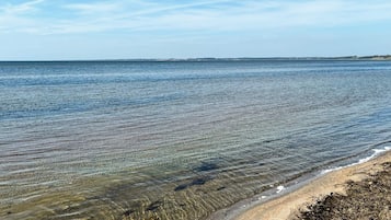 Ein klarer Blick auf einen Strand mit ruhigem Wasser und einer entfernten Küstenlinie.