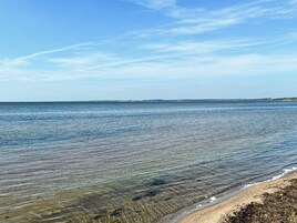 Una vista despejada de una playa con aguas tranquilas y una costa lejana.