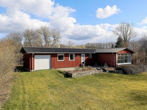 A red single-story building with a white garage door, a small porch, and a window with the name 'BIRKELY' on the door. - 6 Person Holiday Home in Farso (Farso)