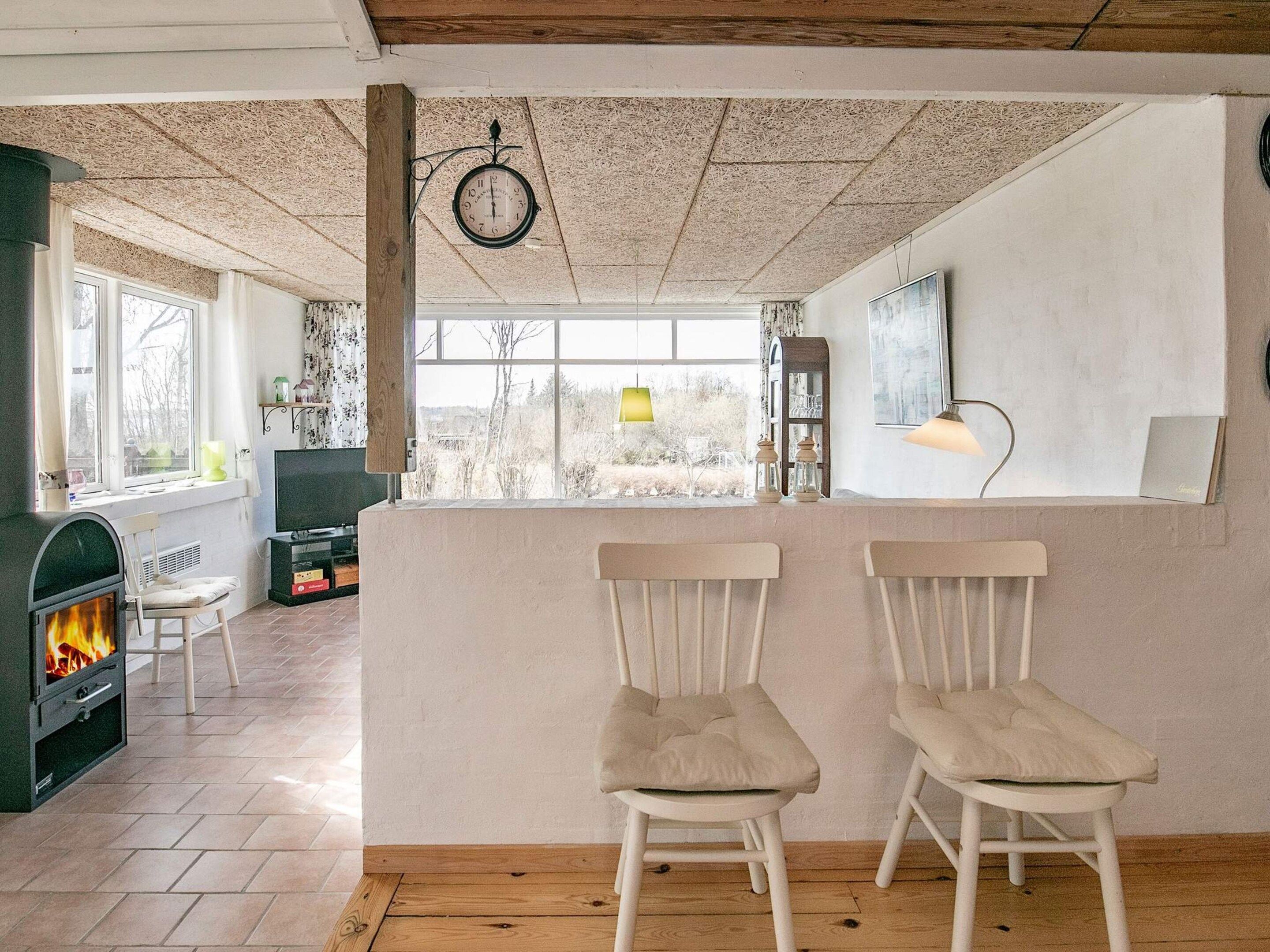 Uma sala de estar acolhedora com lareira, televisão e uma janela grande com vista para o exterior.