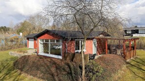 A red house with a large window and a wooden deck. - 6 Person Holiday Home in Farso (Farso)