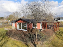 Una casa roja con un ventanal grande y una terraza de madera.