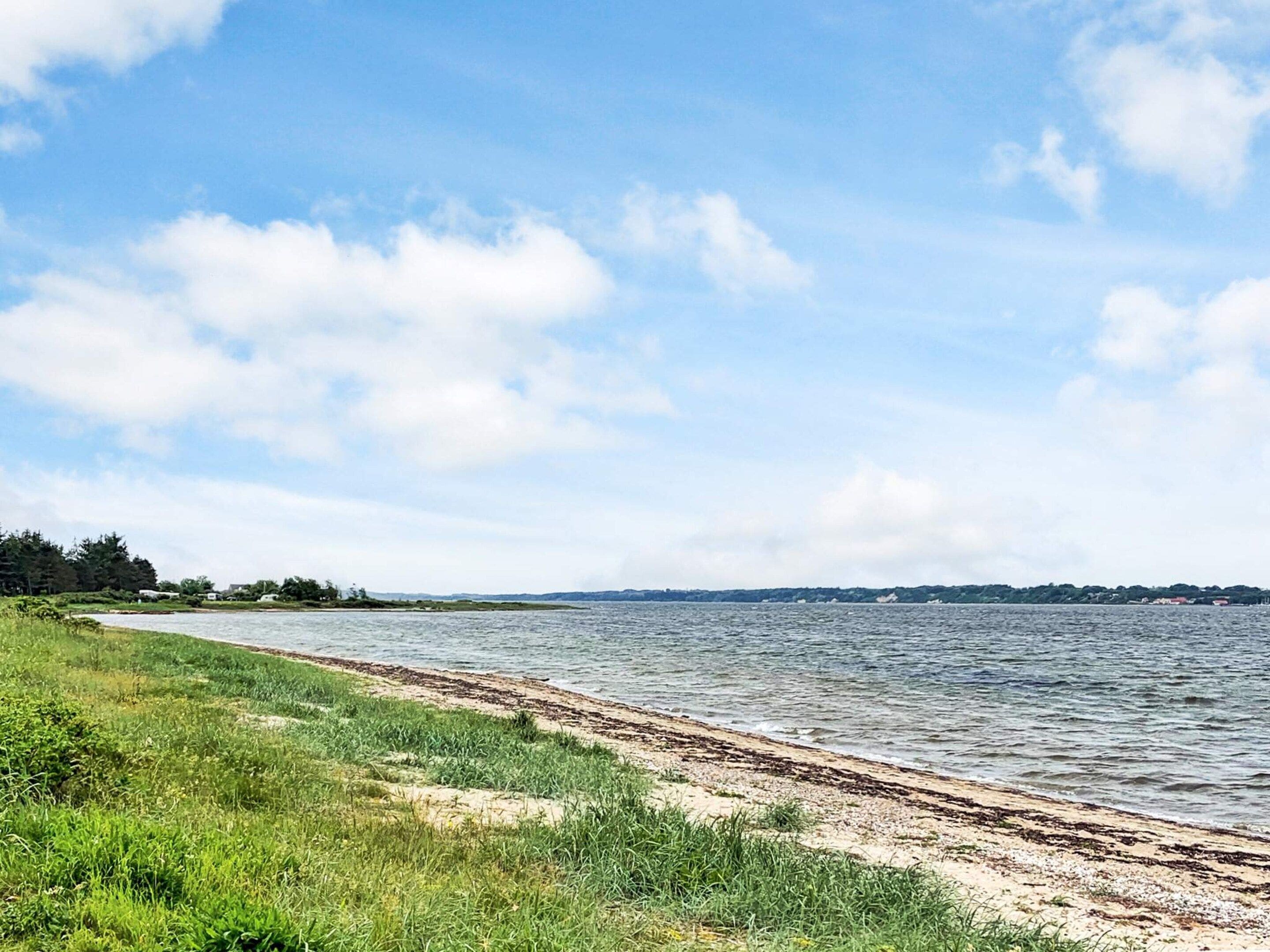 A riverside view with a sandy beach and grassy banks.