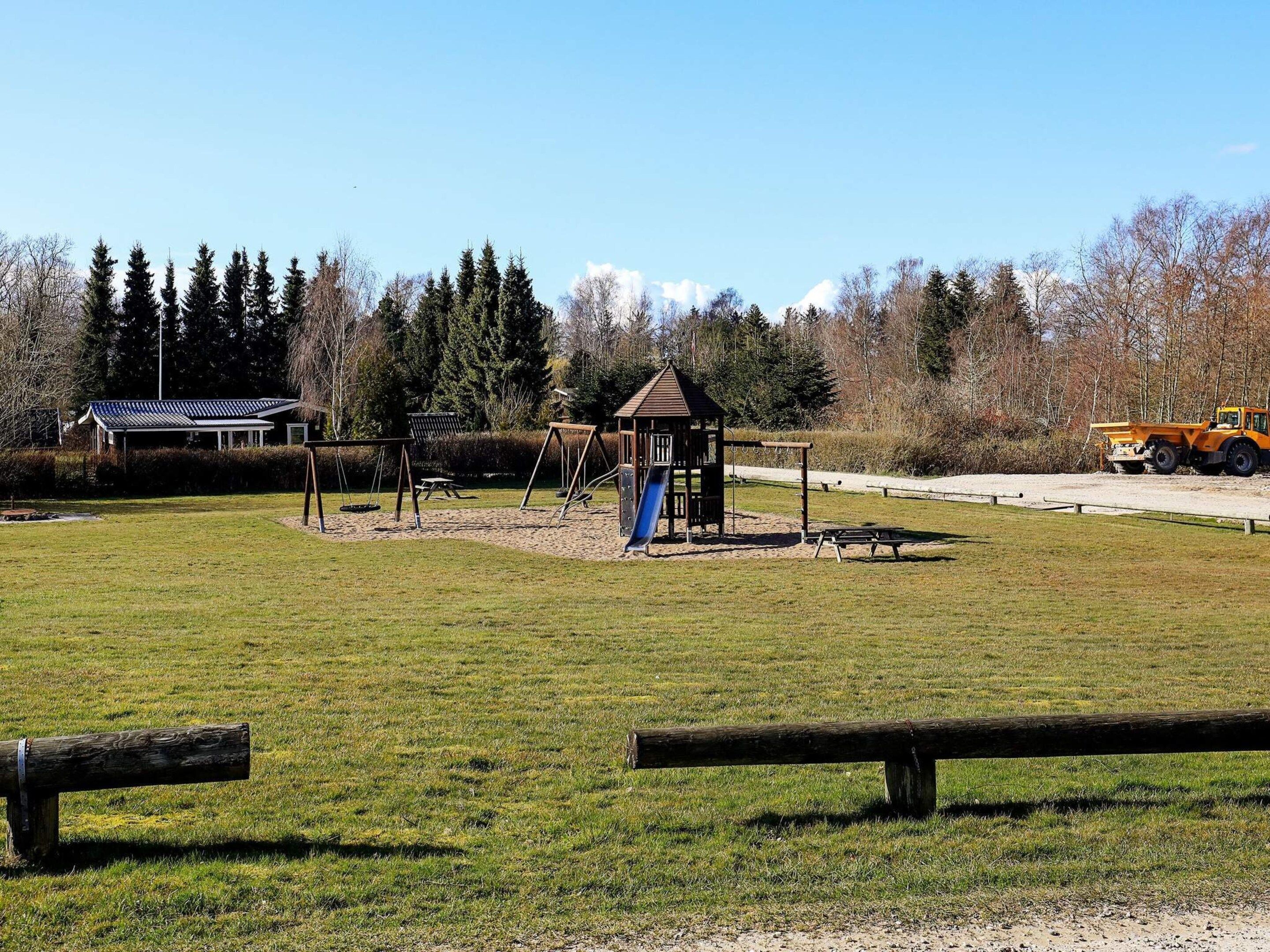 A playground with swings, a slide, and a small shelter.