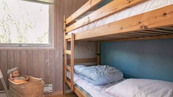 Ein Schlafraum mit Etagenbett, Fenster, Korbsessel und einer Puppe.