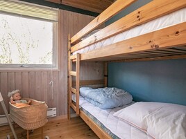 Habitación con literas, una ventana, una silla de mimbre y una muñeca.
