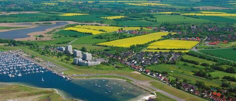 An aerial view of a coastal town with a marina, residential areas, and agricultural fields.