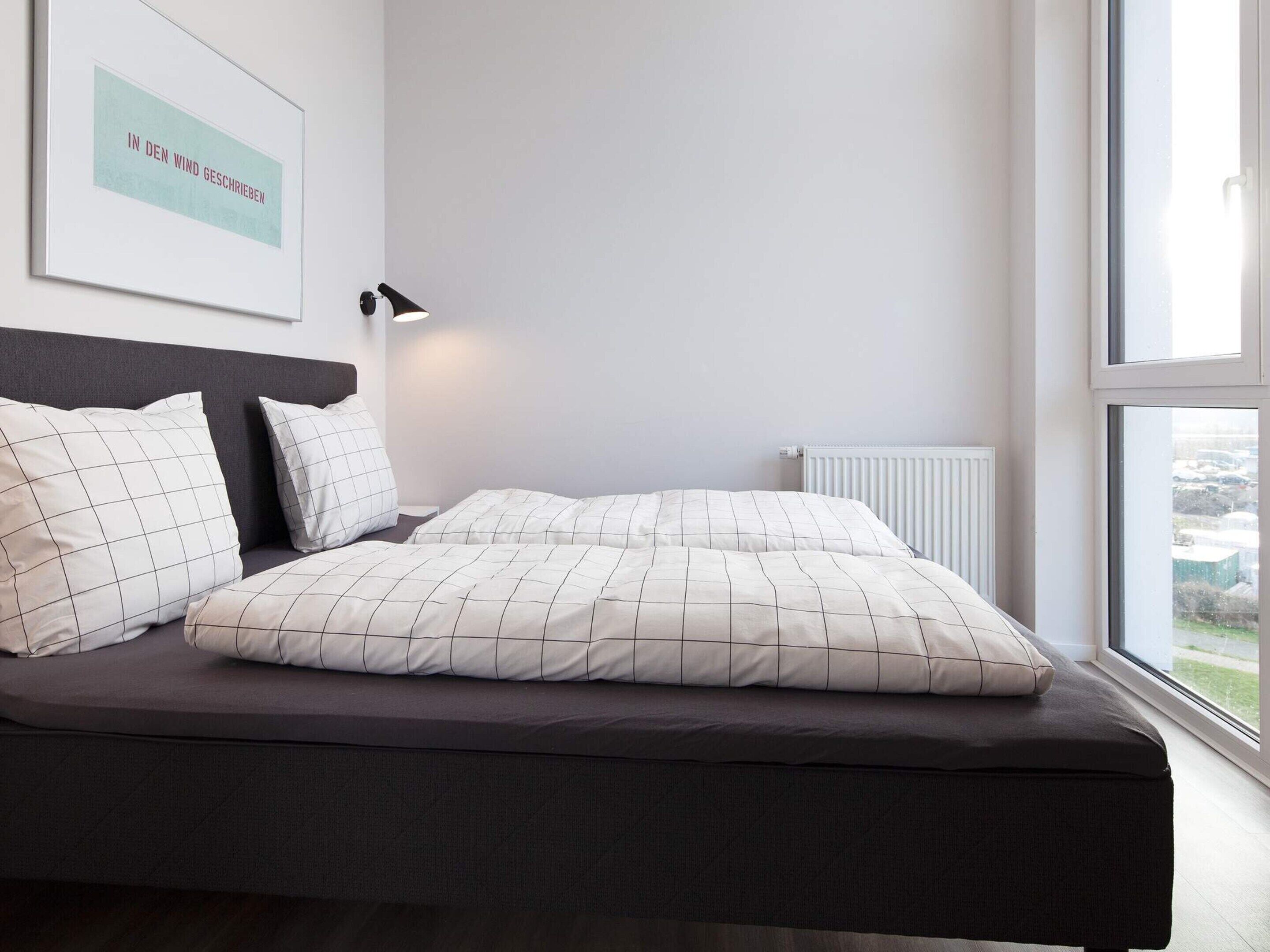Une chambre à coucher moderne avec un lit, des oreillers, une lampe de chevet et une fenêtre donnant sur un beau paysage.