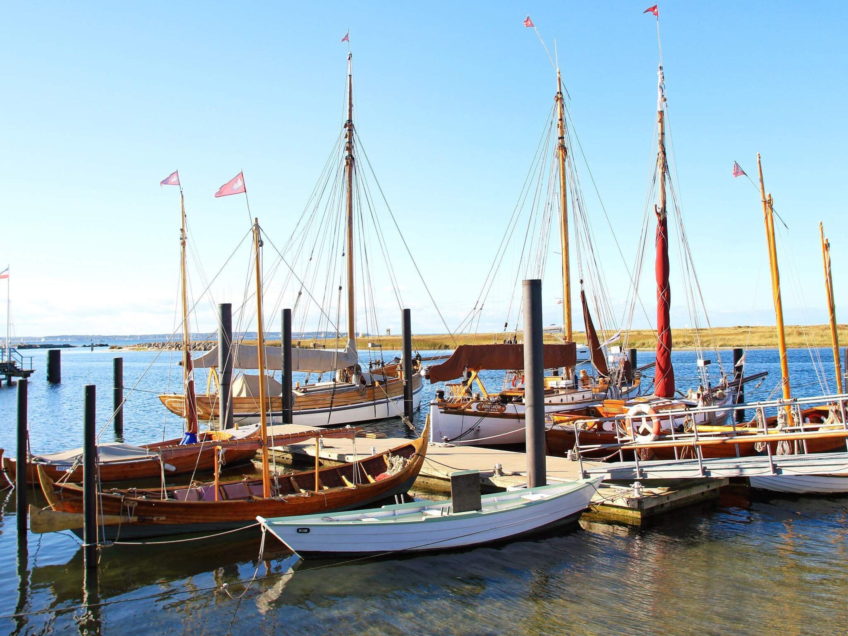 Uma marina com vários barcos atracados, incluindo um barco de madeira com cabine em destaque.