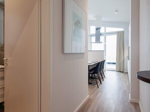 Ein modernes Interieur mit Essbereich, einer Küche und einem Flur, der zu einem Balkon führt.