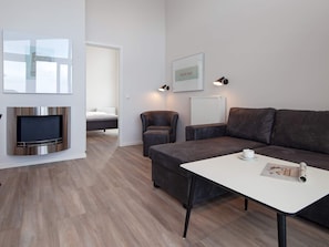 Una sala de estar moderna con un televisor de pantalla plana, un sofá, una mesa de centro y un cuadro en la pared.