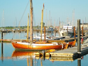 A marina with multiple boats docked, wooden boats, and a clear sky.