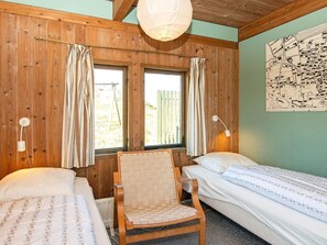 A room with two single beds, a wooden chair, two windows with curtains, a wall map, and a hanging light fixture. - 4 Person Holiday Home in Fano (Fano)