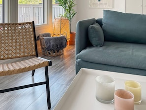 A living room with a wicker chair, a blue sofa, and a tray with candles. - 4 Star Holiday Home in Borgholm (Borgholm)