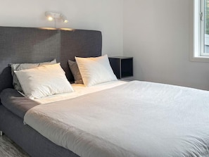 A modern bedroom with a large bed, a headboard, bedside tables, and a window. - 4 Star Holiday Home in Borgholm (Borgholm)