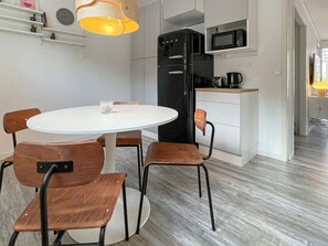 A modern kitchen with a white table and chairs, a black refrigerator, and a microwave. - 4 Star Holiday Home in Borgholm (Borgholm)