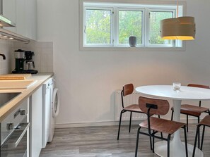 A modern kitchen with a built-in washing machine, a coffee maker, and a dining area with a round table and four chairs.