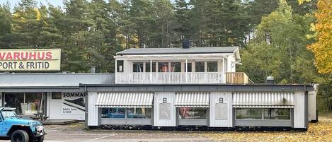 A two-story building with a sign for 'VARUHUS PORT & FRITID' and a blue vehicle parked in front.