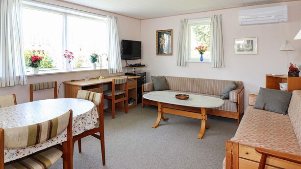 Een gezellige, goed verlichte kamer met een eettafel, een bank en een televisie.
